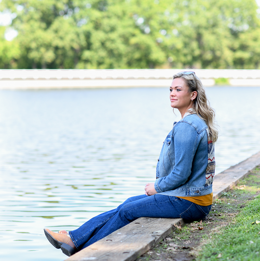 Woman sitting and relaxing by a lake. Meditating for stress relief.