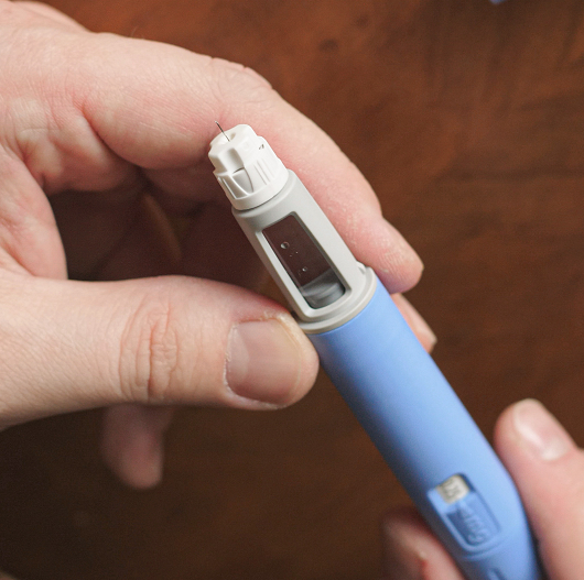 A caretaker prepares a weight-loss drug injection for a child