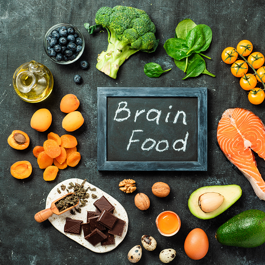 Brain food concept with various food like avocado, salmon and nuts on a chalkboard.
