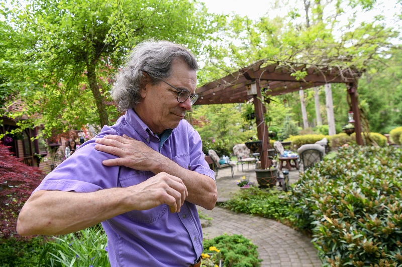 Man holds his shoulder in pain, experiencing a rotator cuff injury