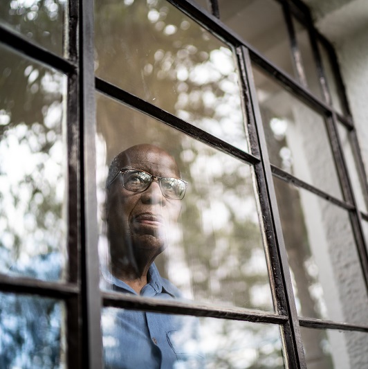 Senior man looking through the window at home