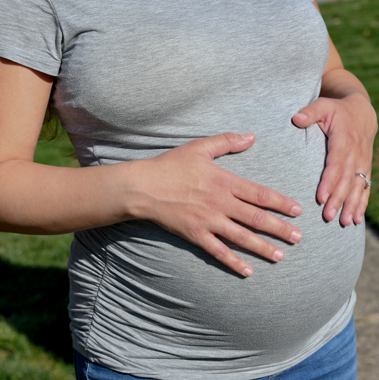Pregnant woman feeling her belly - why abdominal separation happens during pregnancy