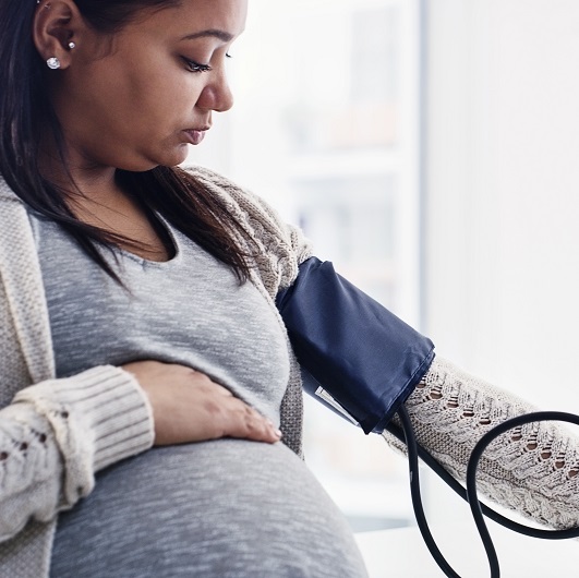 A pregnant young woman getting her blood pressure checked by a doctor at a clinic