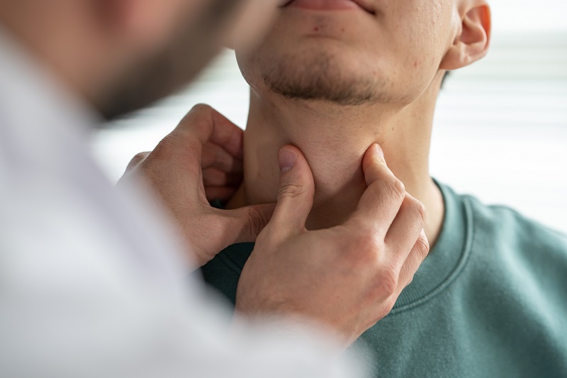 Doctor examining patient's throat and thyroid