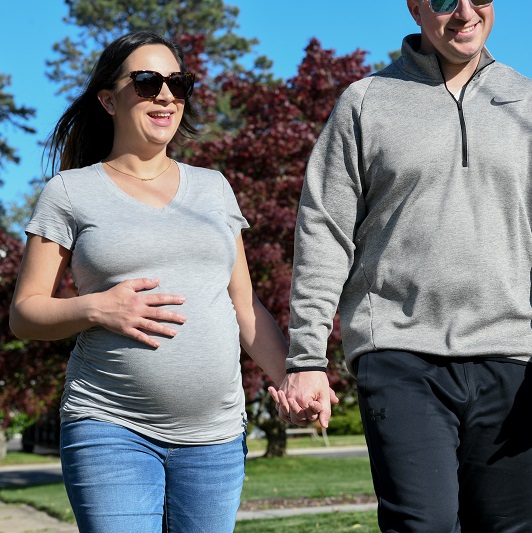 Pregnant woman walking with her husband outside to get exercise.