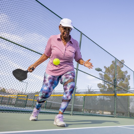 Older woman about to hit a ball in a pickleball match.