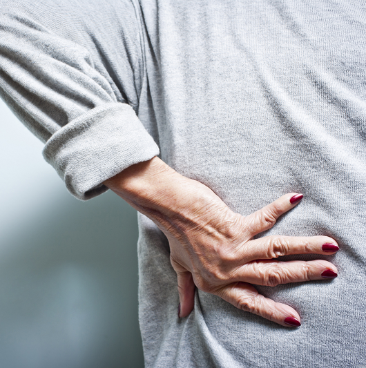 Elderly woman with a back ache from arthritis pain.