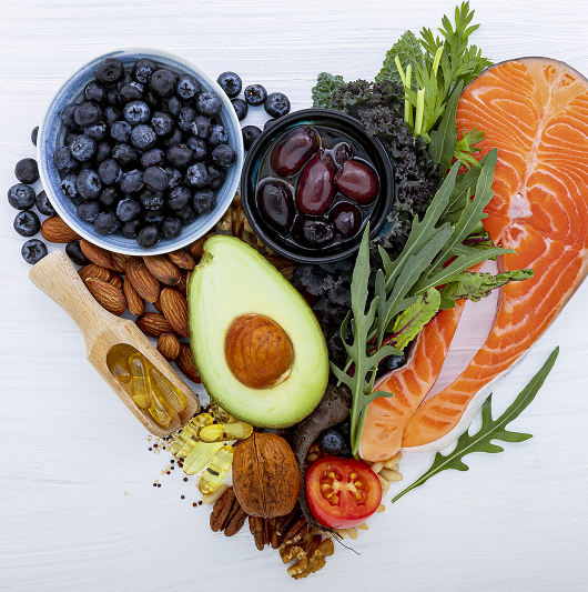 Heart shape of heart healthy foods. Ingredients for healthy foods selection on white wooden background.