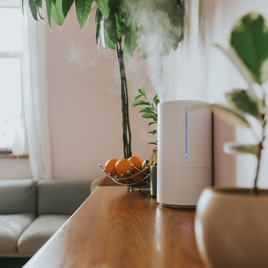 A humidifier releasing steam on a counter space in a living room.