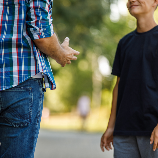 A father talking to his teenage son outside.