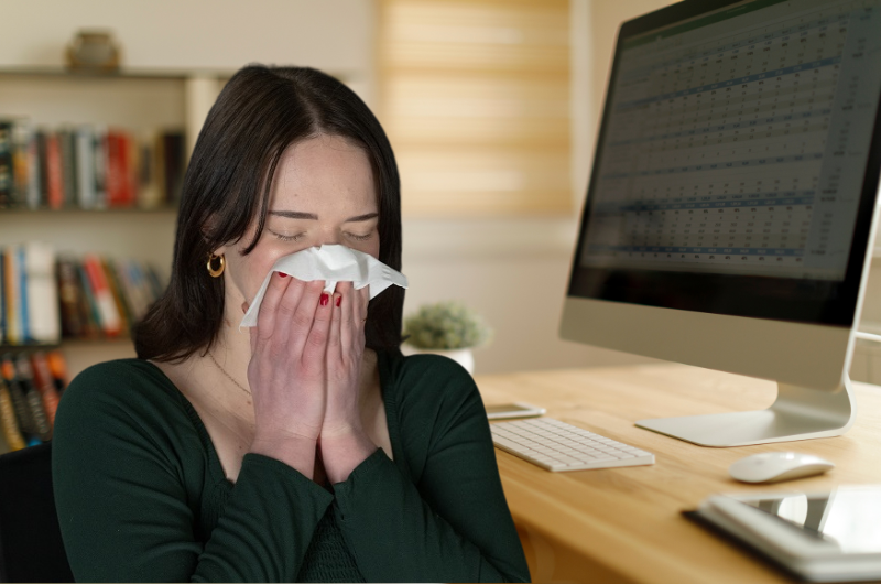 Young woman blowing her nose at home.