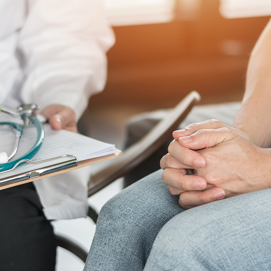 Woman has her hands in her lap, nervous, during a doctor's visit.