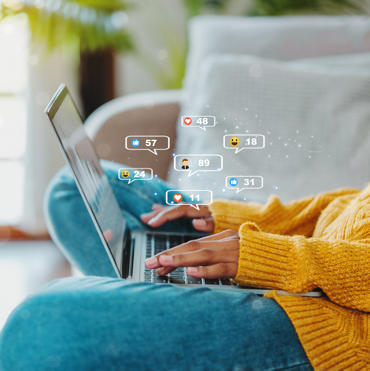 Woman using a laptop on the couch, on social media sites with notifications popping up.