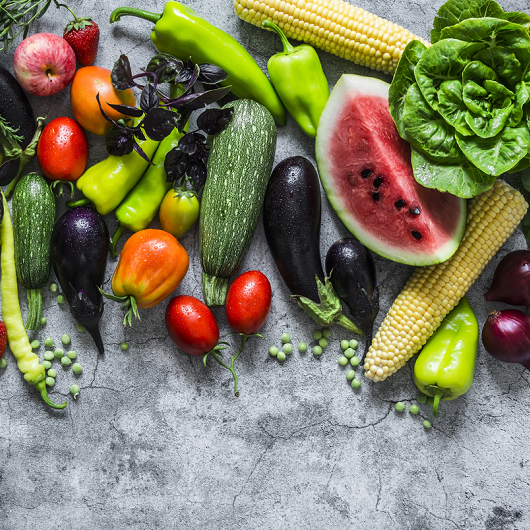 Fresh garden organic vegetables, berries, and fruits on a gray background, top view.