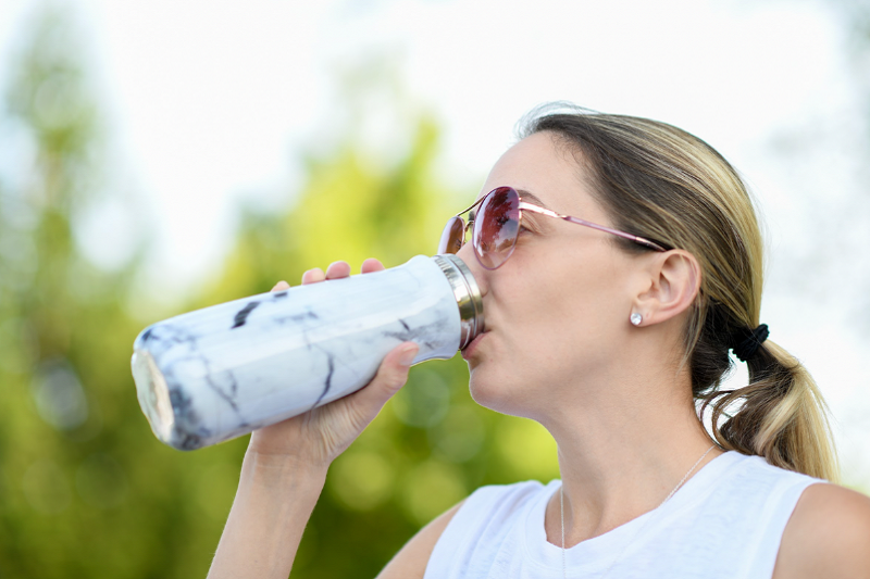 A woman takes a drink from her water bottle during a workout. A woman takes a drink from her water bottle during a workout.