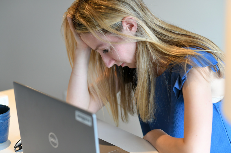 A young woman with a painful migraine holds her hand to her forehead.