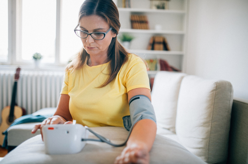 Photo of a woman checking her blood pressure at home.