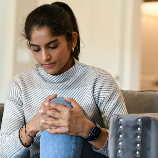 Young woman clutches her knee while sitting down.