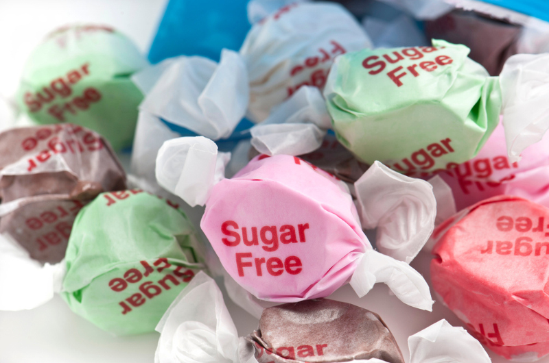 Sugar-free candies coming out of the bag on white background.