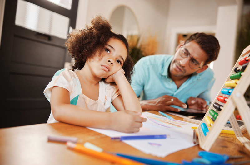 Little girl stares off into the distance, looking bored, while her father watches her.