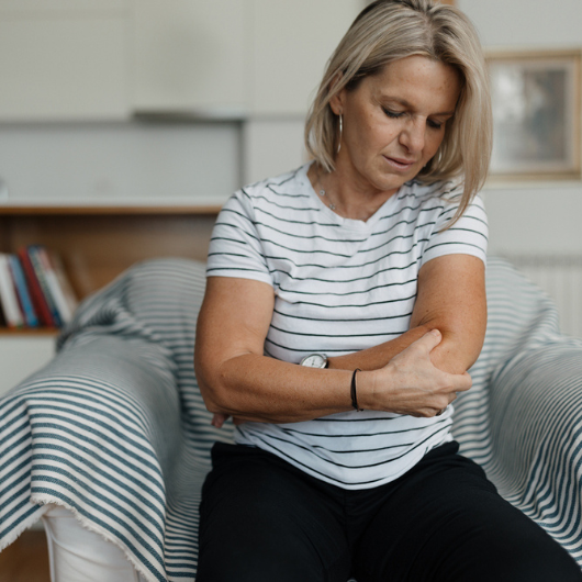 Middle-aged adult woman having elbow pain.