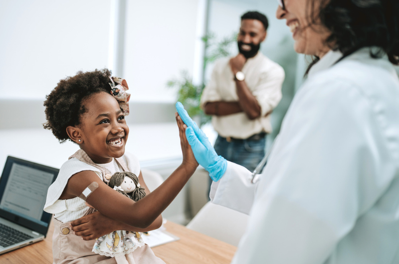 Happy child high-fives her doctor after being vaccinated.