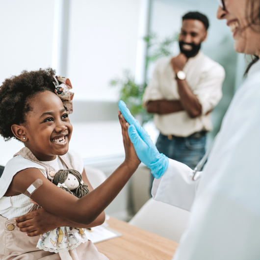 Happy child high-fives her doctor after being vaccinated.