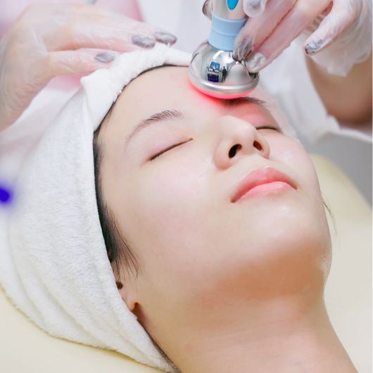 Image shows a close-up of a woman receiving a non-surgical laser treatment on her face.