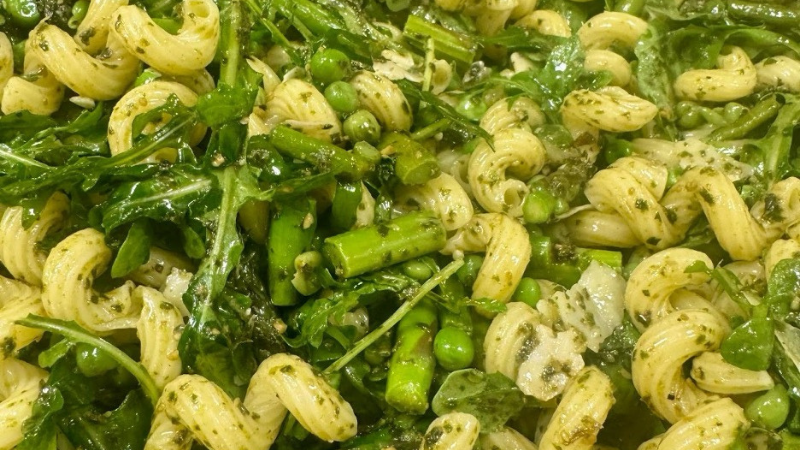 Top-down view of spring pasta salad made with vegetables, pasta and fresh herbs.