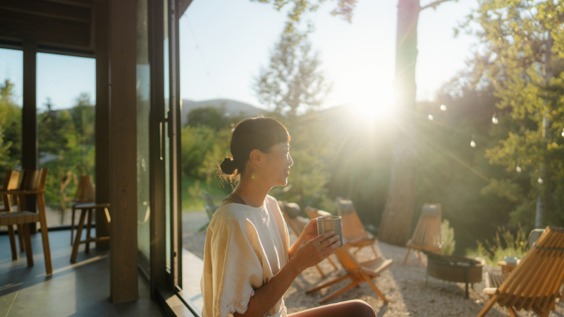 A woman sipping a warm cup of tea in the morning, basking in the sun.