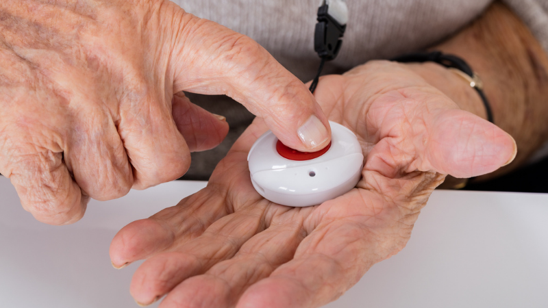 Close-up of senior woman pressing a medical alert system for an emergency.