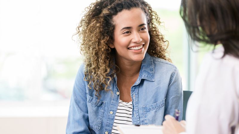 A smiling female patient attentively listens as a doctor gives her good news.