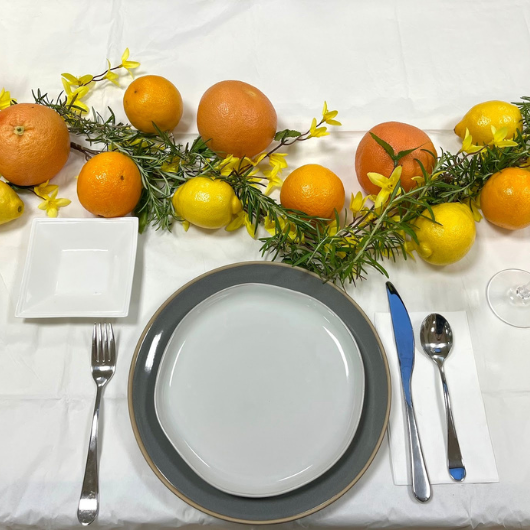 Top-down view of a decorated tablescape with a citrus and yellow floral garland.