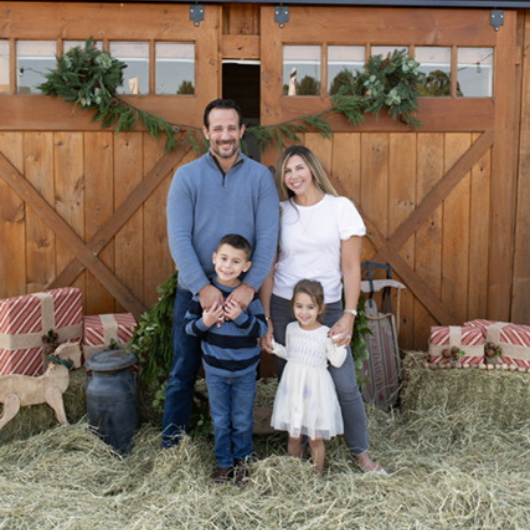 Lisa Silber poses in front of a barn door with her partner and two young children.