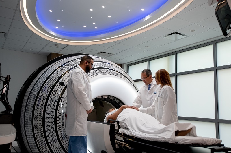 ZAP-X and Synaptive MRI imaging machine. A patient laying on their back about to have a scan, with physicians around them.