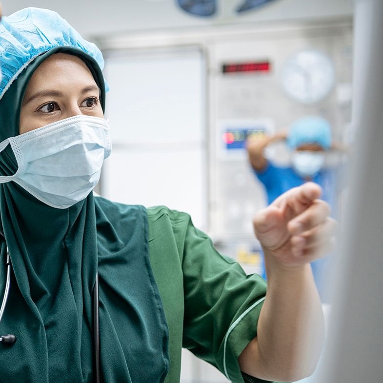physician with a mask on looking at a screen