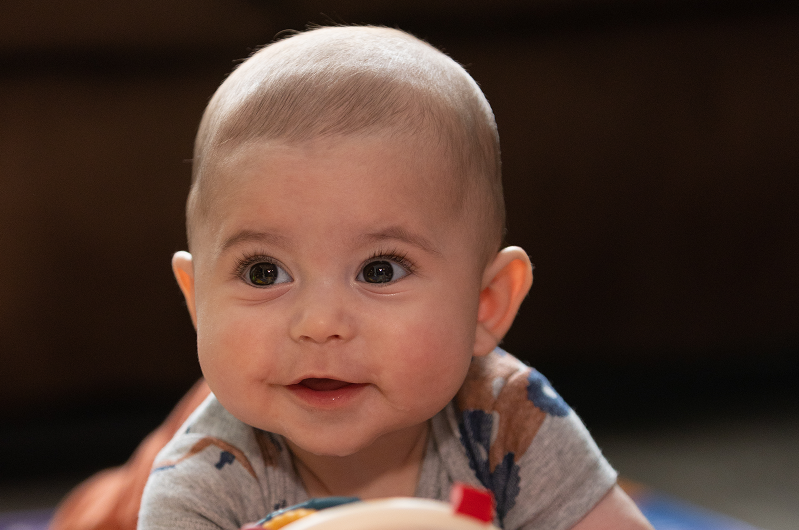 Baby Benny doing some tummy time, with his toys, smiling.