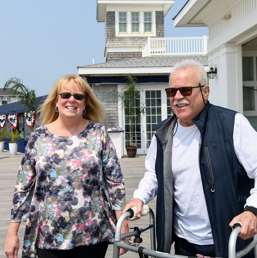 Tom and his wife walking on the boardwalk smiling.