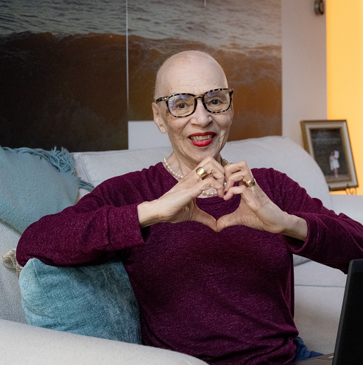 Rose C. smiling and holding her hands in a heart shape.