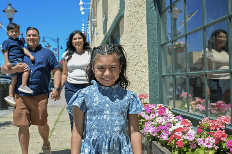 A little girl who received a kidney transplant smiles at the camera as her mom, dad and little brother look on.
