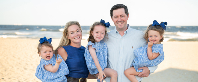 Allison Adams stands on a beach with her husband and three young daughters.