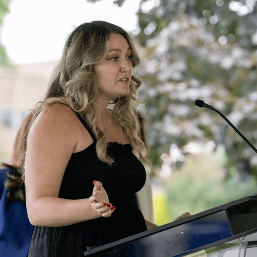 Michelle Colucci stands at a podium and speaks.