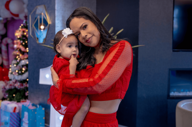 Wearing all red, Ann Marie Oseguera holds her daughter close while looking at the camera.