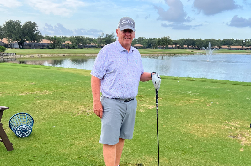 Standing on a golf course, 69-year-old Jim Schleifer holds his golf club.