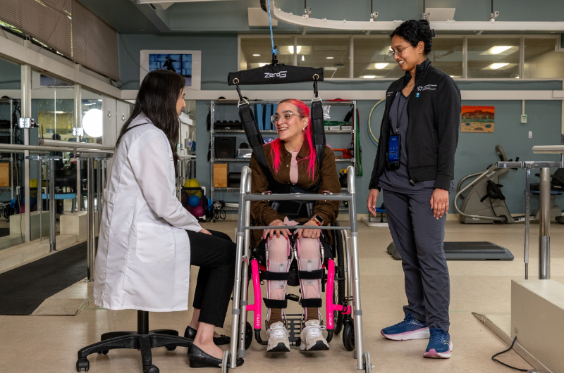 Giannina Feliciano sits and smiles at her Hackensack Meridian Health care team.