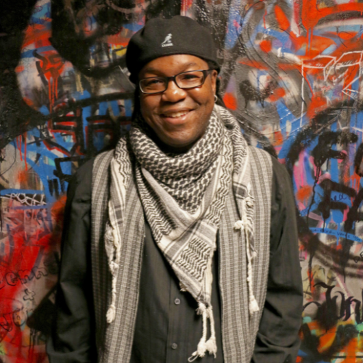 Jakubu Griffin of Teaneck, New Jersey, stands in front of a colorful wall and smiles.