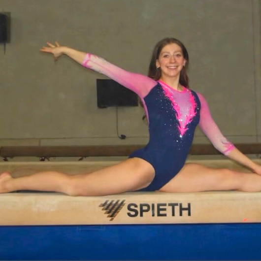 Image shows Hackensack Meridian Health patient, Zoe Lenz, posing in a split position on a balance beam.