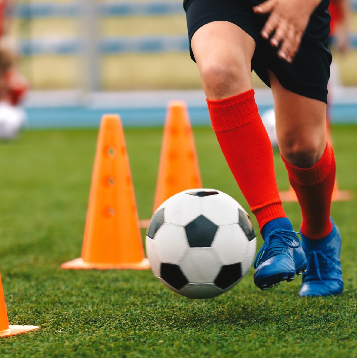 kid kicking soccer ball between cones
