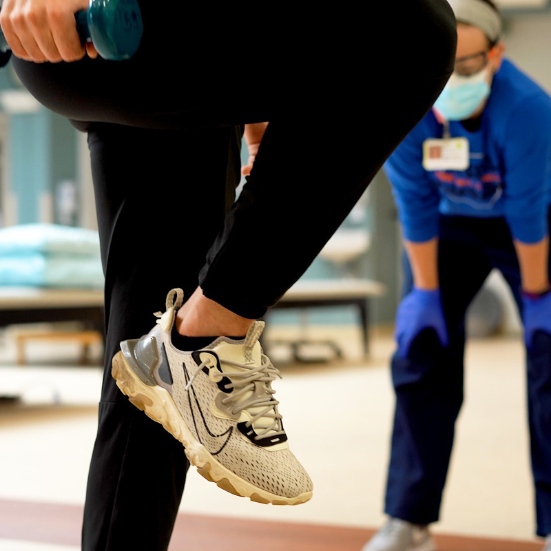 person holding weights and standing on one leg