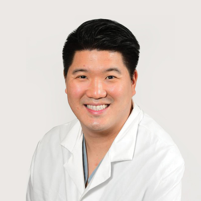 Man wearing white jacket with short black hair and smiling